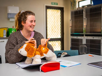 A student holding a stuffed puppy.