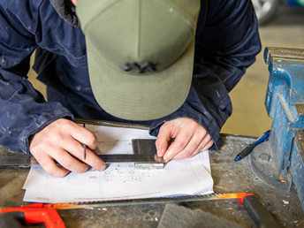 A student drawing on a paper using a stensil