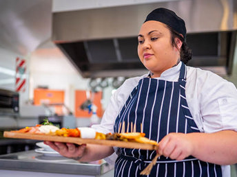 A UCOL cookery student carrying a platter.